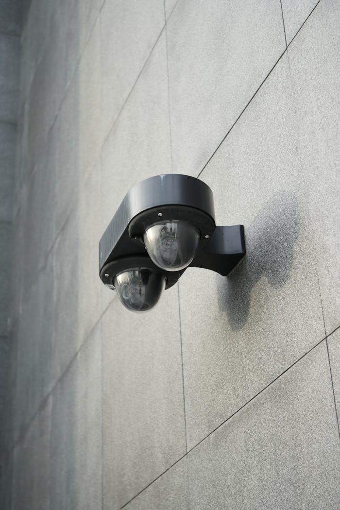 A security camera mounted on a sleek gray concrete wall for monitoring